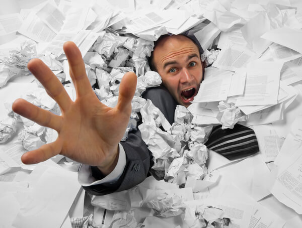 Business man stuck under a pile of bookkeeping paperwork