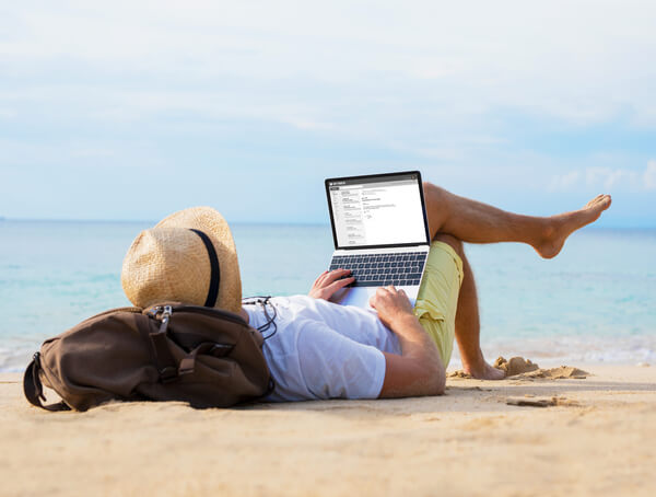 Business owner doing bookkeeping work on laptop at beach